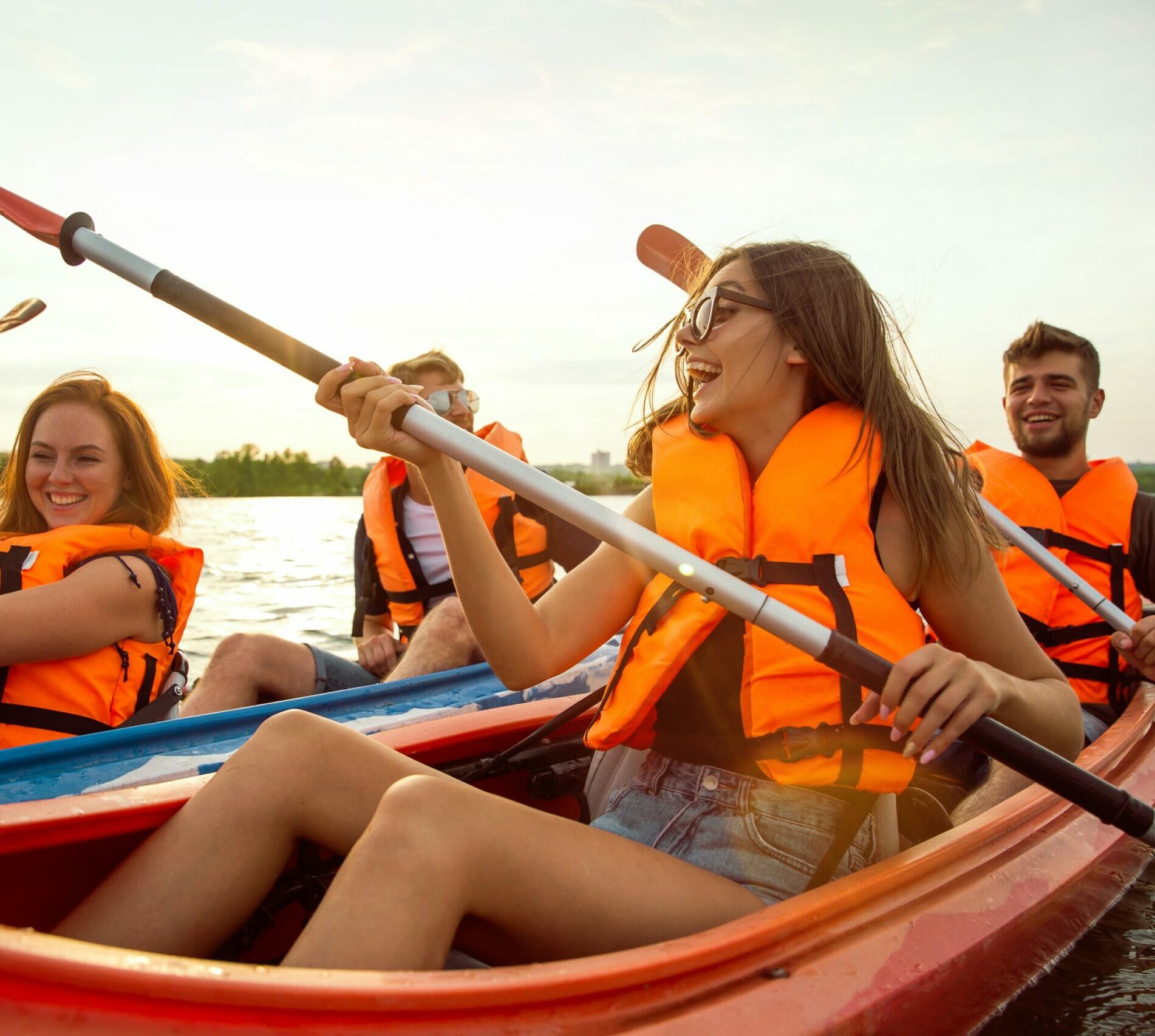 fröhliche-Freunde-Kajakfahren-Fluss-mit-Sonnenuntergang-Hintergrund-min